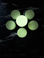 Pale green round Baja Breeze conditioner bars arranged in a flower-like pattern on a dark marbled surface