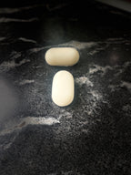 Two oval shaped soaps on a dark marbled surface
