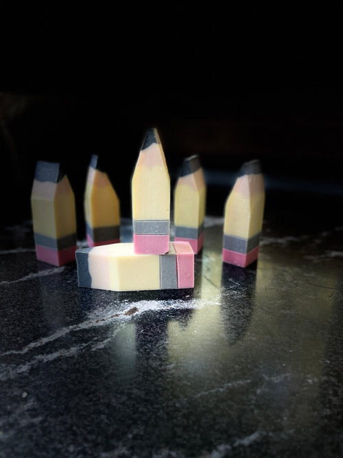 Small chunky soaps shaped like pencils arranged on a dark marbled surface