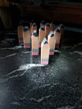 A set of miniature wooden pencils standing upright on a dark, marbled surface