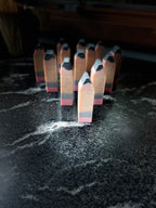 A set of miniature wooden pencils standing upright on a dark, marbled surface