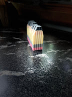 A stack of crinkle cut pencil soaps standing upright on a dark, reflective countertop.