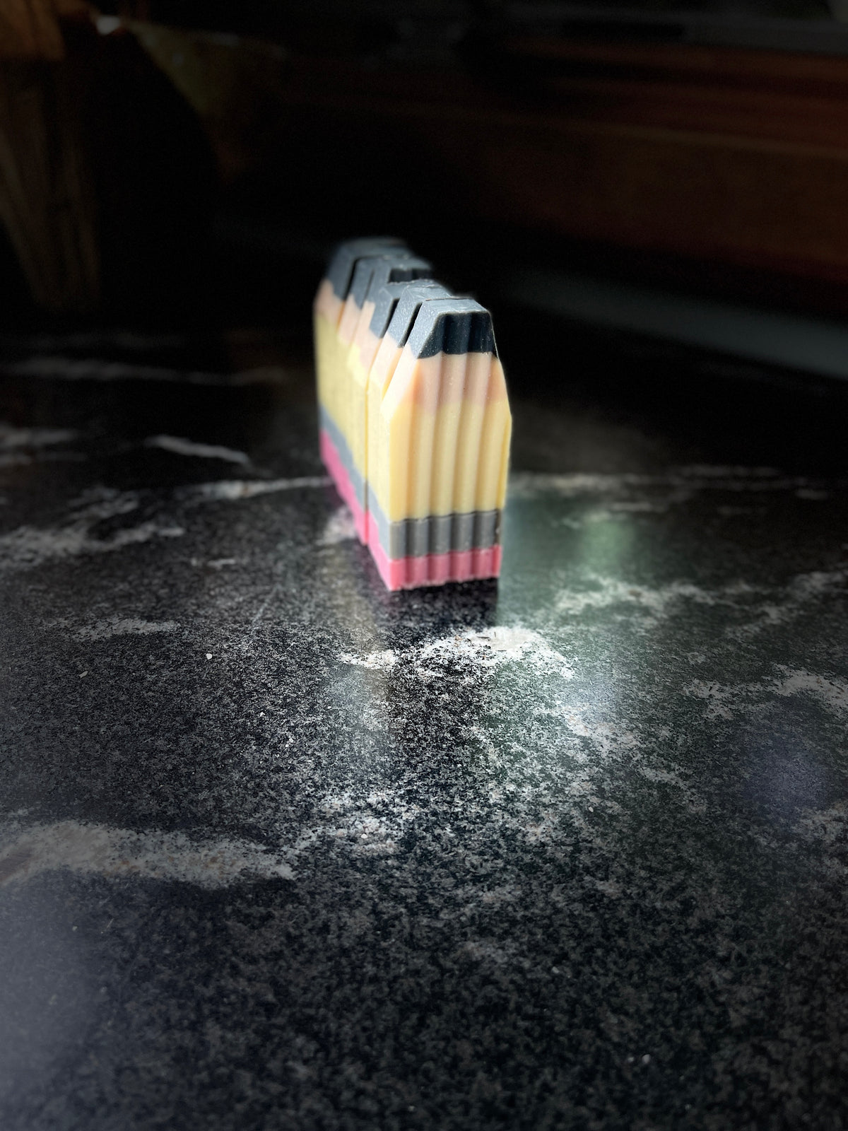 A stack of crinkle cut pencil soaps standing upright on a dark, reflective countertop.