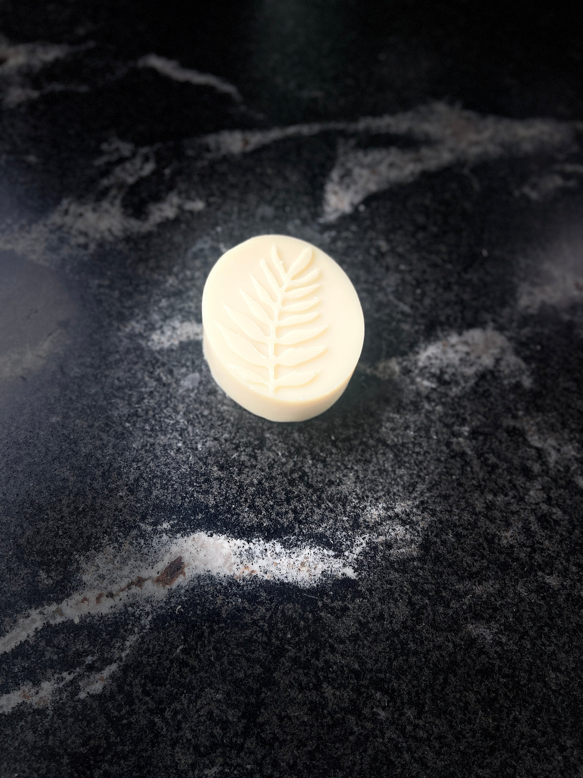 One single ovalish bar of soap with a leaf embossed on the front