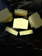 Several pale yellow bars of Savi Suds soap arranged on a dark marbled surface, with the brand name stamped on the tops.