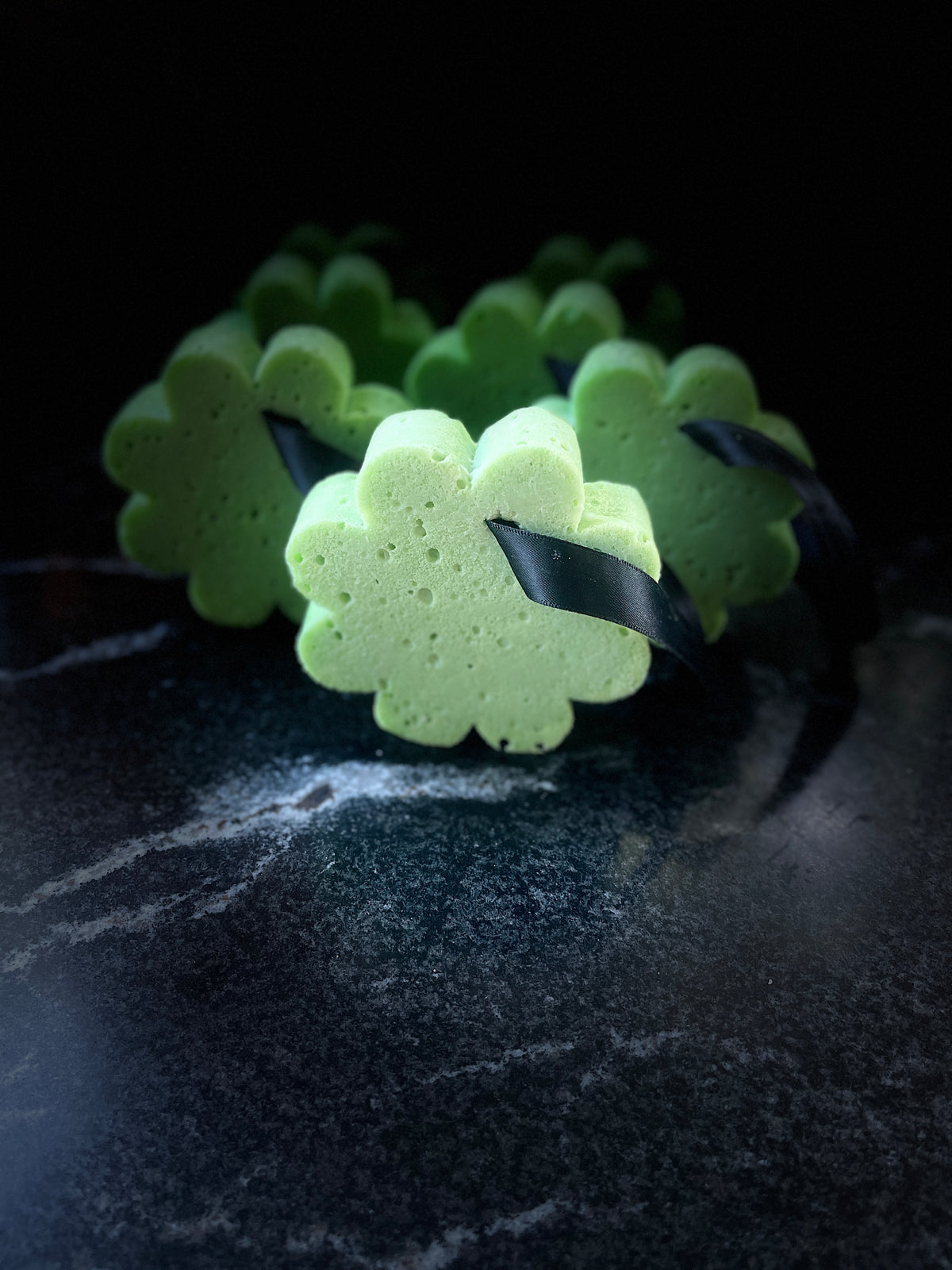 Several green soap sponges arranged on a dark textured surface