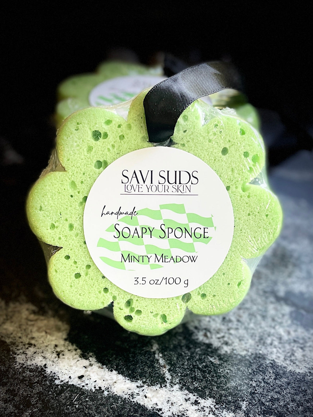 Green soap sponge with a label on a dark textured surface