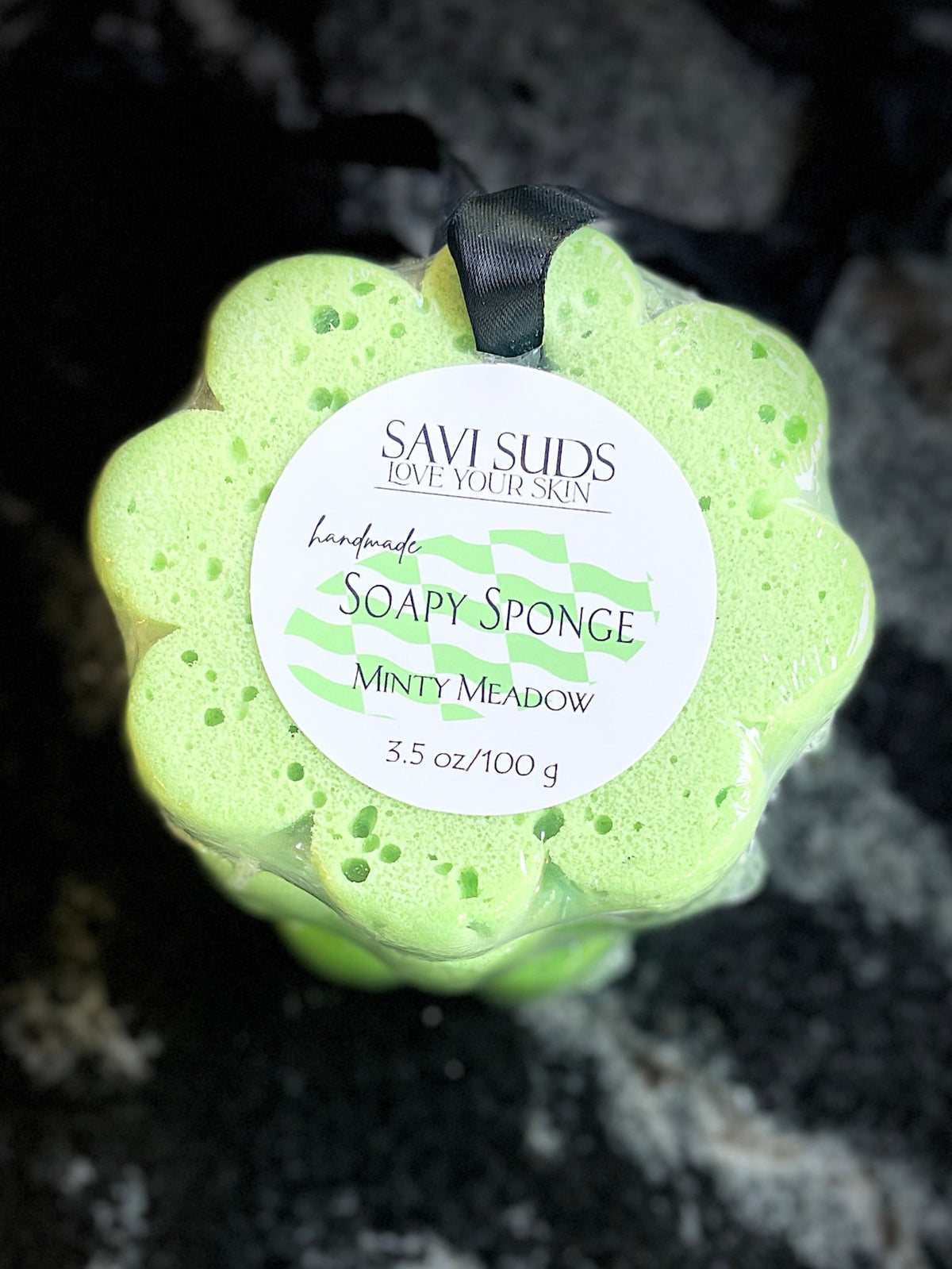Green soap sponge with a label on a dark textured surface