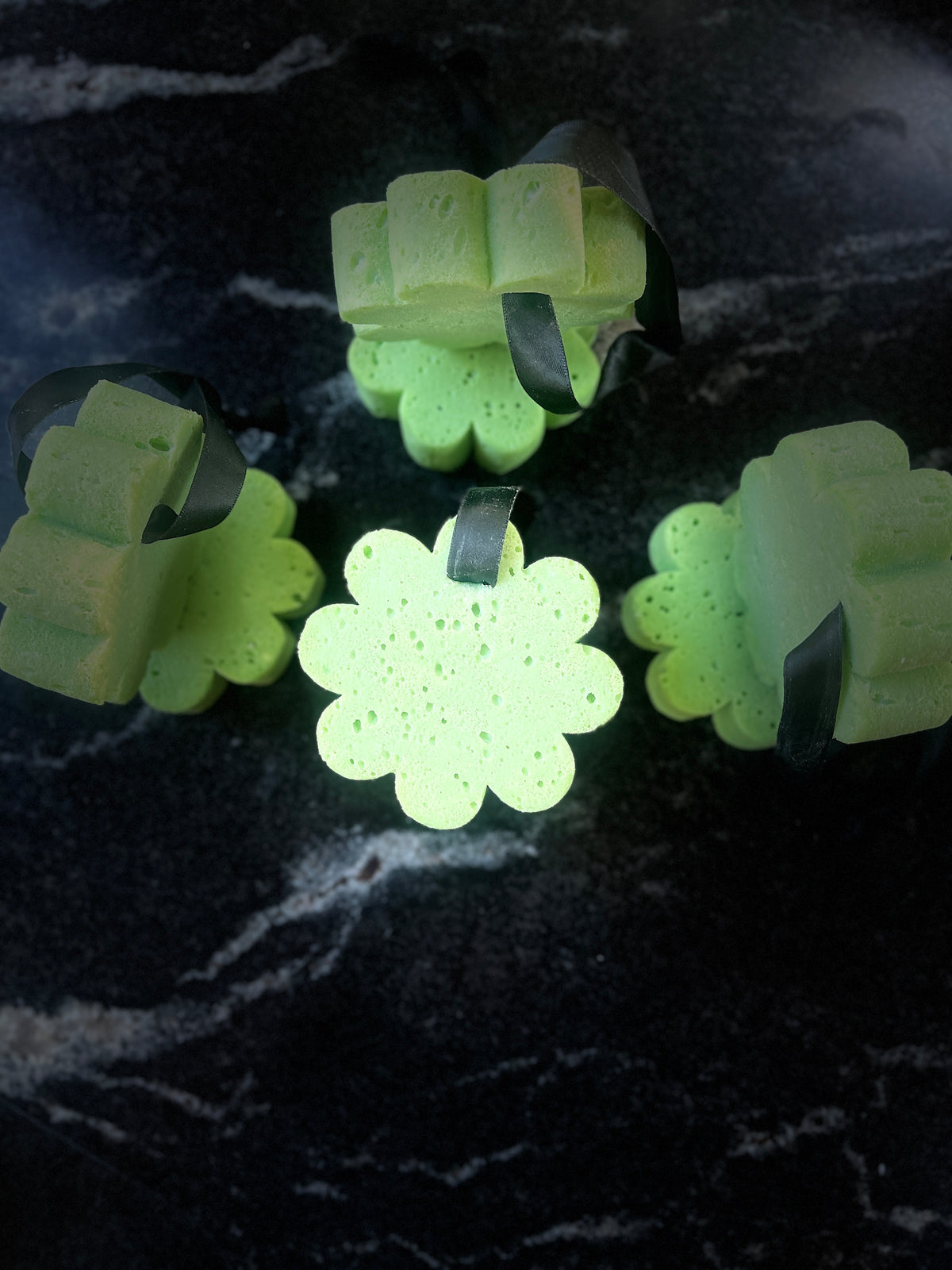 Several green soap sponges arranged on a dark textured surface