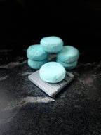 Ocean Orchid round shampoo bars arranged on a marbled surface with one bar in front on top on a squared gray stone plate