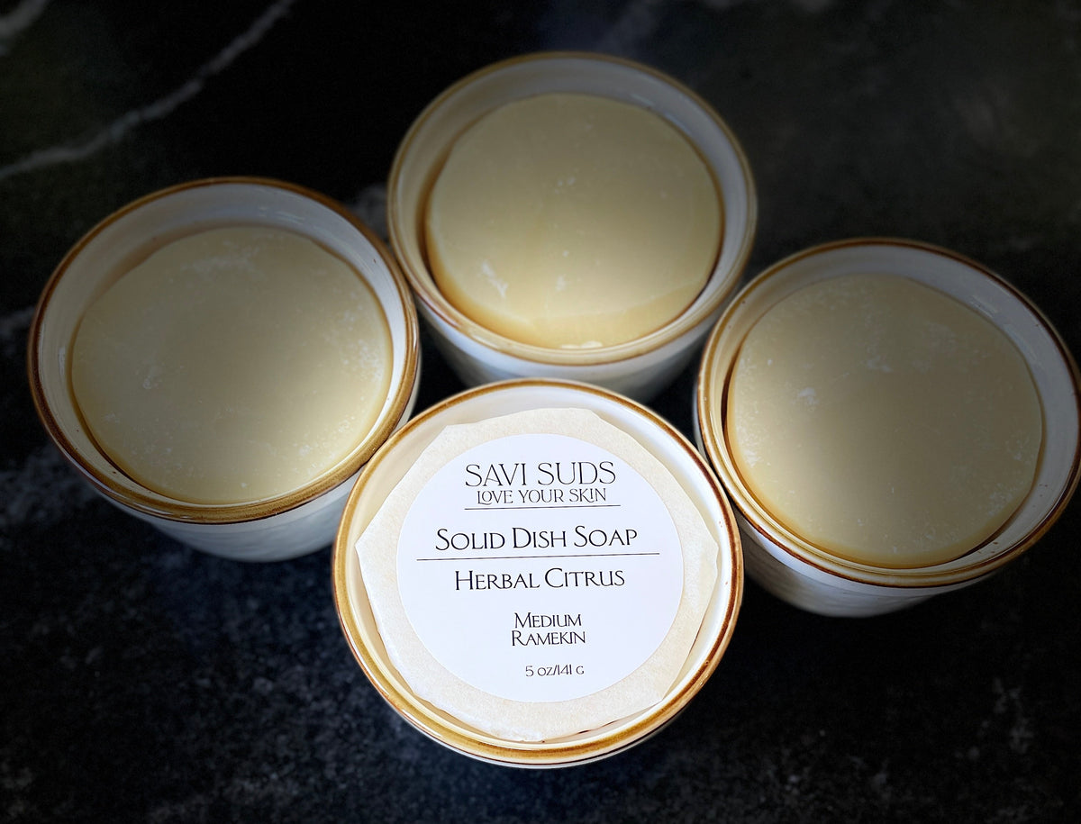 Solid Dish Soap in ramekins with brown rim. Foreground picture has a wrapped soap with Savi Suds Herbal Citrus scent